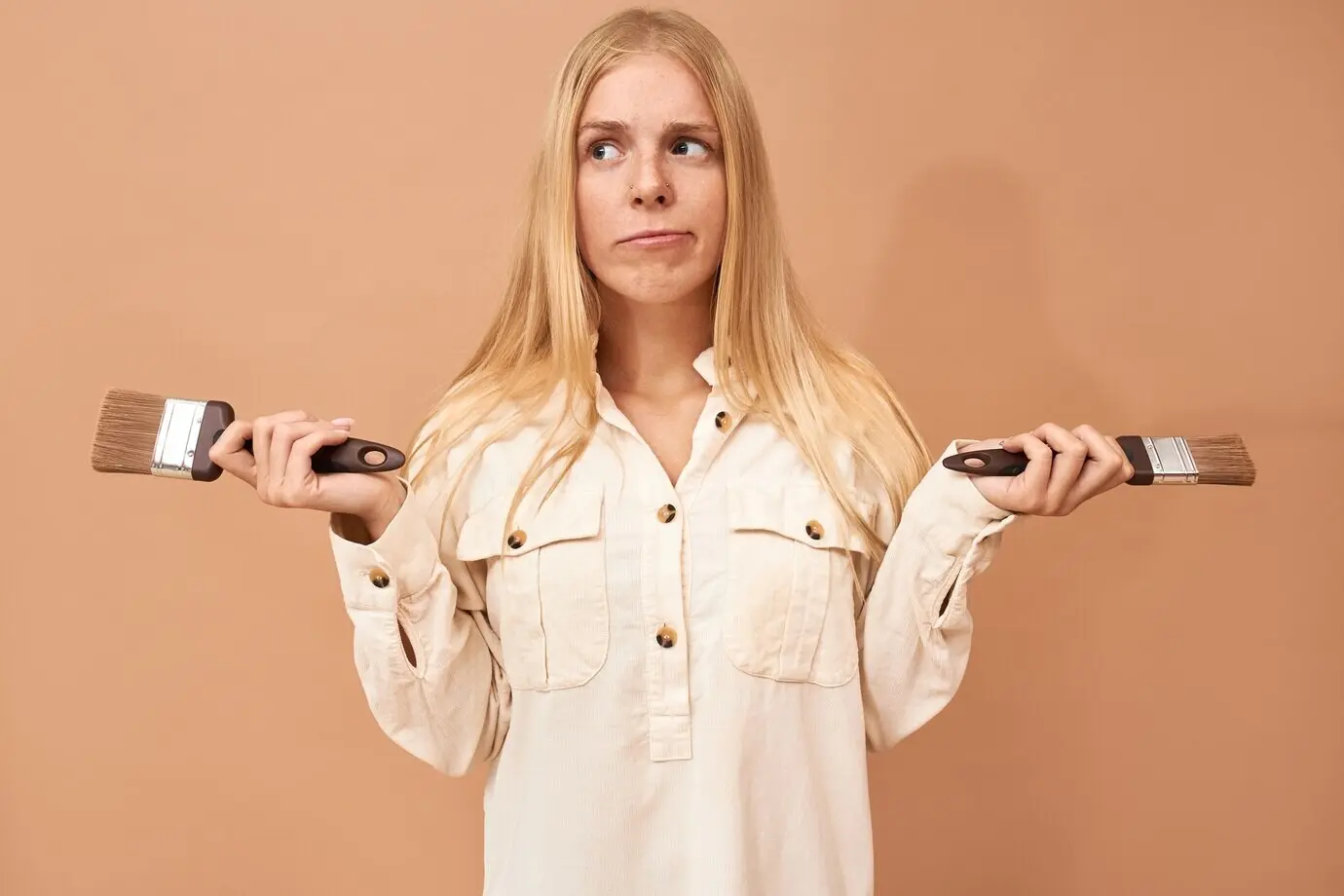 Porträt einer hübschen Teenagerin mit Zahnspange und langen Haaren, die beim Streichen von Innenwänden spezielle Werkzeuge einsetzt, um diese vor Schäden durch Wasser oder Korrosion zu schützen.