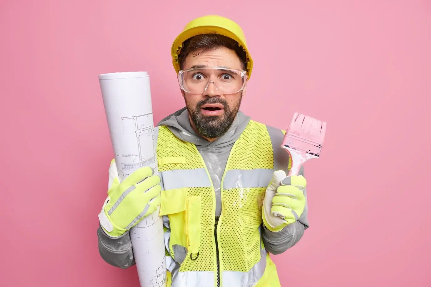 Ein Mann, der bei Hausrenovierungsarbeiten tätig ist, bietet professionellen Reparaturservice an, hält einen Malerpinsel, erstellt einen architektonischen Bauplan und trägt Schutzkleidung.